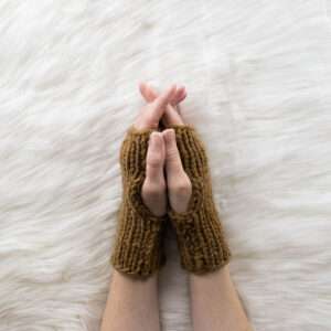 hand model wearing chunky fingerless gloves on a faux fur blanket