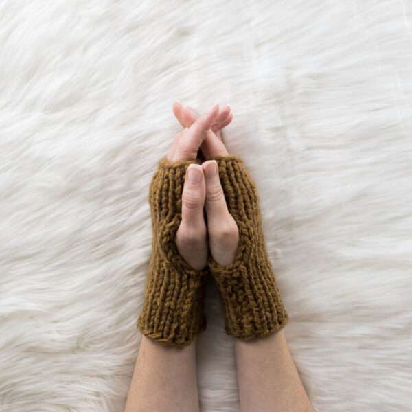 hand model wearing chunky fingerless gloves on a faux fur blanket