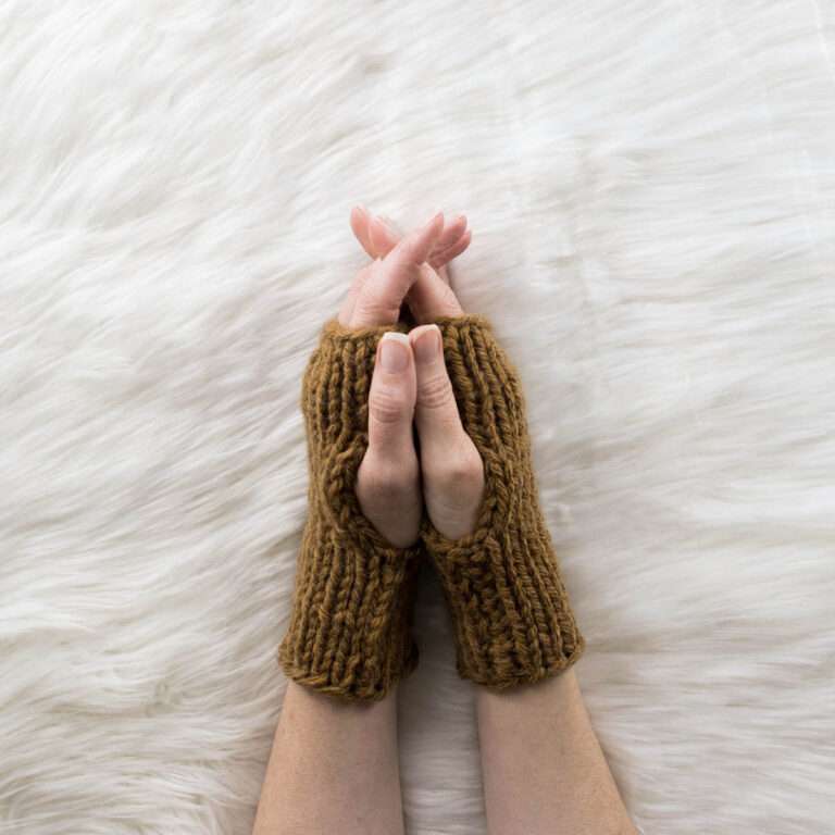 hand model wearing chunky fingerless gloves on a faux fur blanket