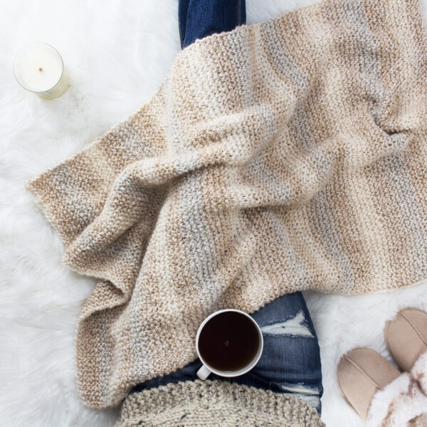 pic of a hand knit blanket on a faux fur rug.