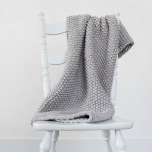 cozy knit seed stitch blanket displayed on a chair