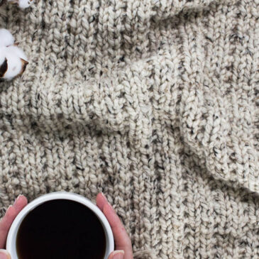 Chunky knit blanket on a faux fur blanket with a cup of coffee.