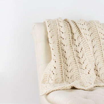 hand knit chunky lace blanket draped over a chair