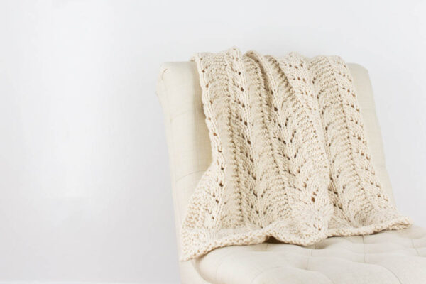 hand knit chunky lace blanket draped over a chair