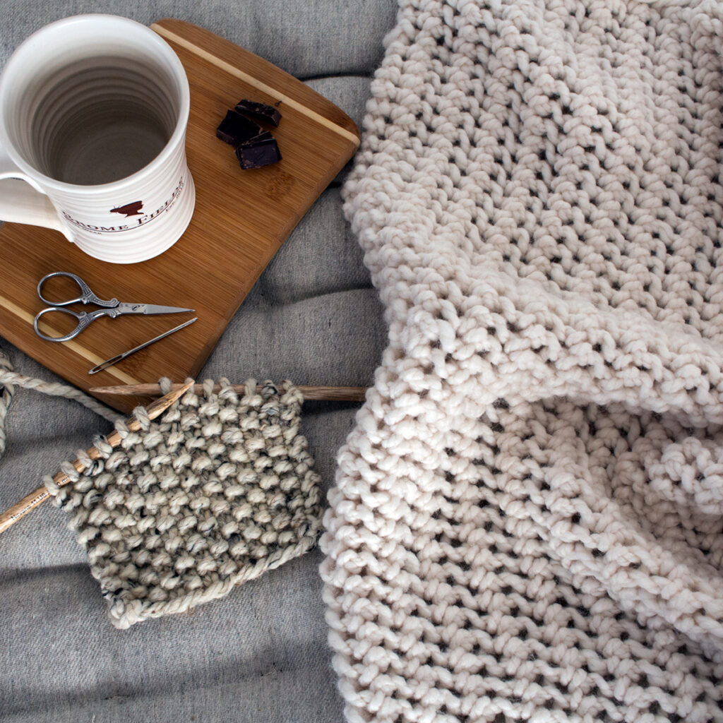 crochet knit blanket on a cushion with a knitted swatch