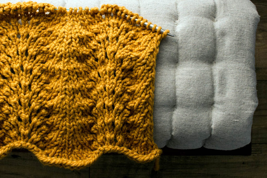 partially knit lace blanket on a cushion