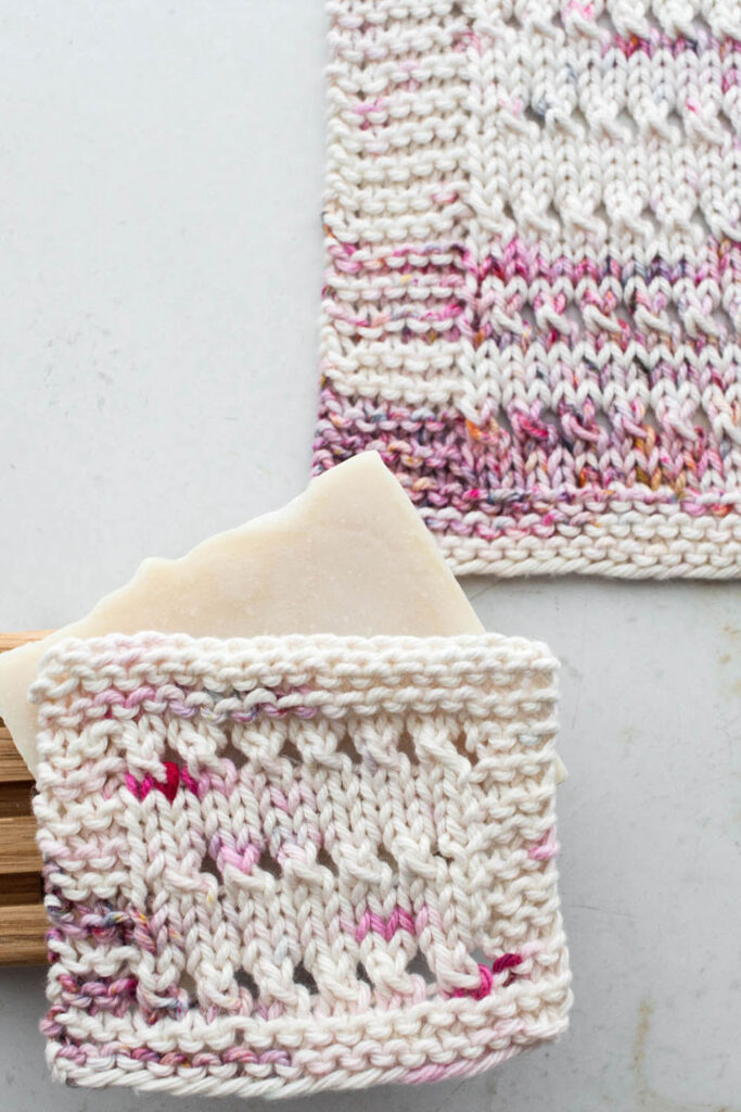 pic of a knitted eyelet dishcloth on a table with a bar of soap on a wooden tray