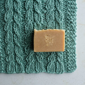 pic of a cable knitted dishcloth on a table with a bar of soap