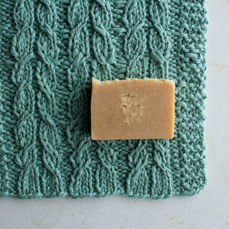 pic of a cable knitted dishcloth on a table with a bar of soap