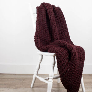 Chunky Knit Blanket draped over a wooden chair.