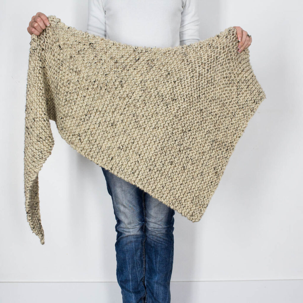 model holding a chunky knit shawl in front of them