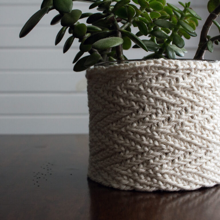 a potted plant with a herringbone stitch knitted cozy cover