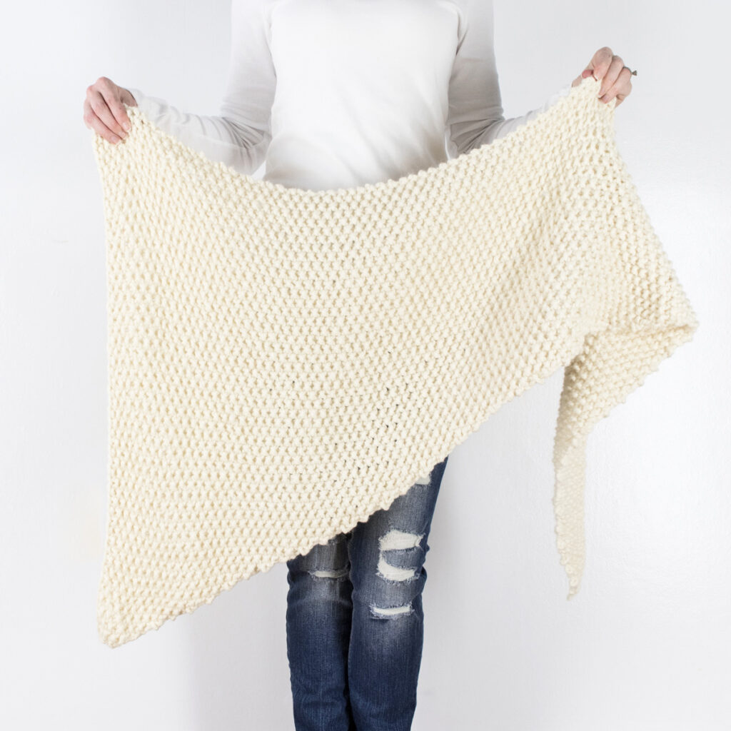 model holding a hand knit chunky triangle shawl
