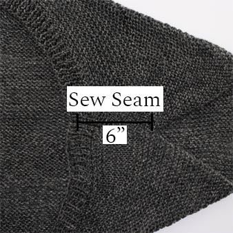knitted shrug laying flat on a table displaying the seam