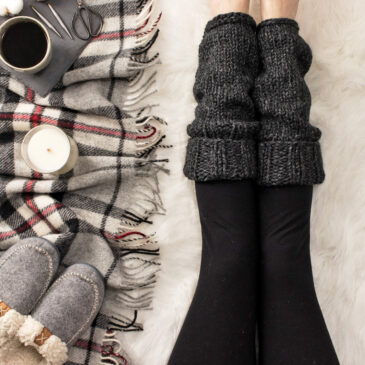 model wearing leg warmers in a cozy setting with a coffee, candle and a blanket & slippers.