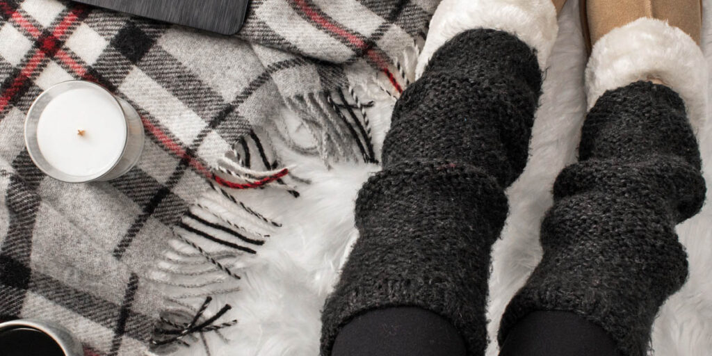 two needle leg warmers on a model a faux fur blanket in a cozy setting