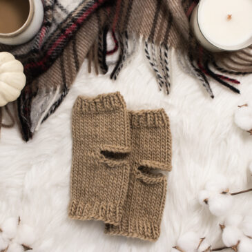 cozy scene of knitted yoga socks on a faux fur blanket with a candle, flannel blanket & cup of coffee.