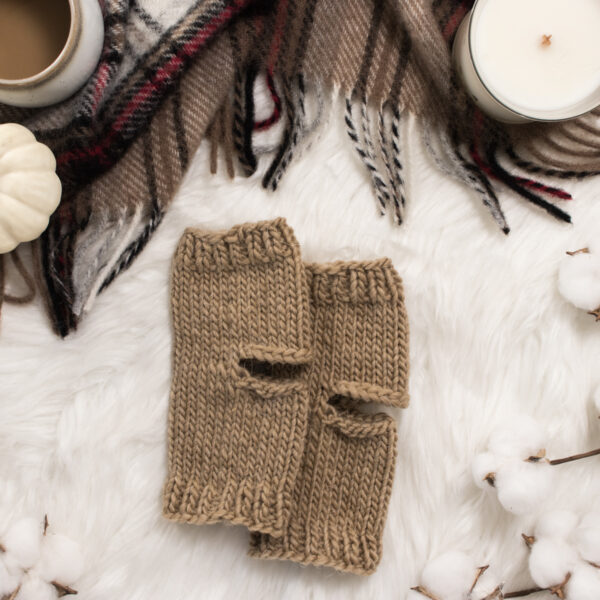 cozy scene of knitted yoga socks on a faux fur blanket with a candle, flannel blanket & cup of coffee.