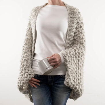 lace knit scoop shrug on a model wearing jeans and a t-shirt holding a mug