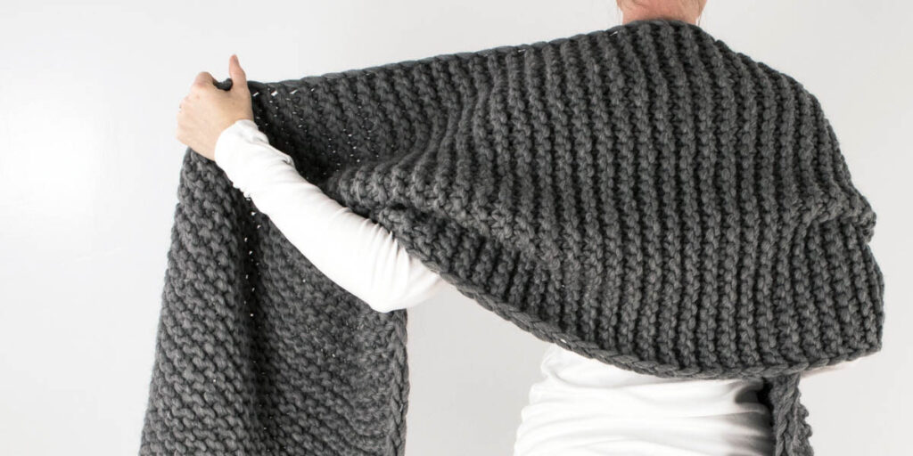 knitted chevron blanket scarf draped over a models shoulders.