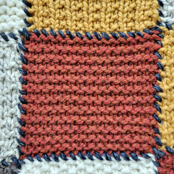 garter stitch swatch on a patchwork blanket