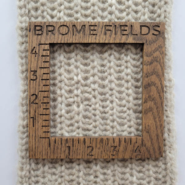 knitted swatch with a wood gauge