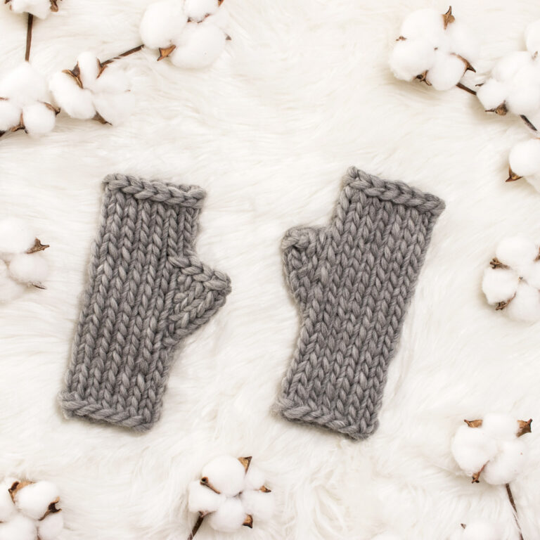fingerless gloves knit in the round laying on a faux fur blanket