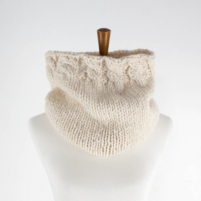 a chunky cable cowl displayed on a dress form
