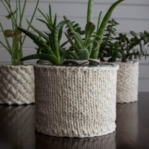 pic of a beginner stockinette stitch knitted plant pot holder covering a pot with a plant in it