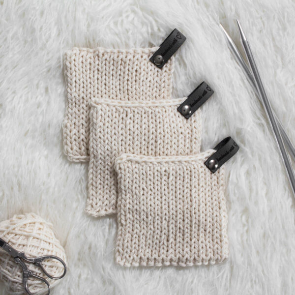 3 hand knit potholders displayed on a faux fur rug