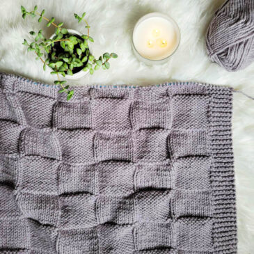 quilted blanket on knitting needles in the process of being knitted