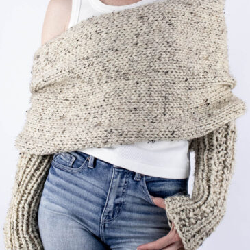 Front view of chunky sweater scarf worn over white tank with ribbed sleeves