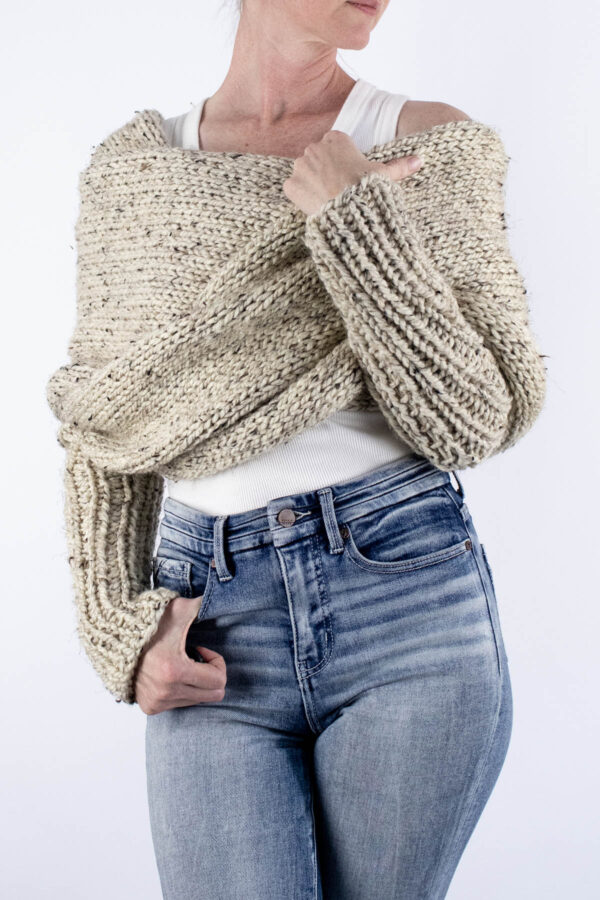 Close-up of chunky knit sweater scarf wrapped around shoulders with ribbed sleeve
