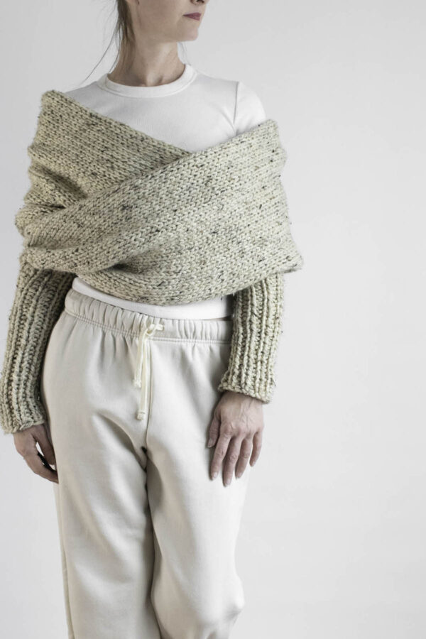 Chunky knit sweater scarf with sleeves styled over white top and beige joggers