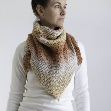 Model wearing the cozy triangle shawl with the tip in front as a cozy scarf cowl.