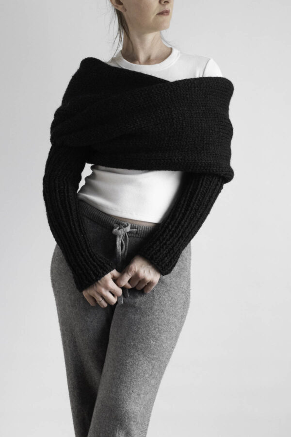 Black knit sweater scarf with sleeves worn over white tee and gray joggers