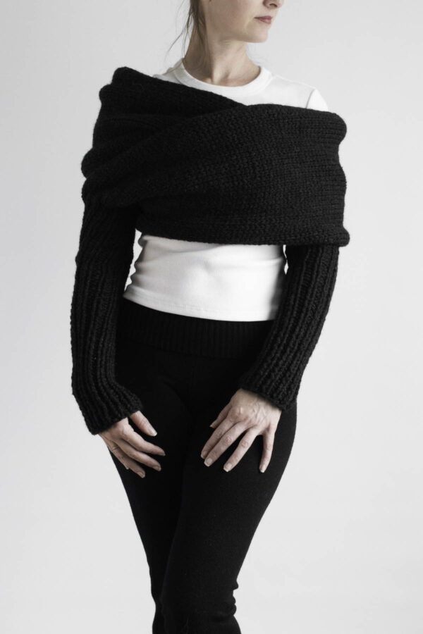Black sweater scarf with long ribbed sleeves styled over white top and black leggings