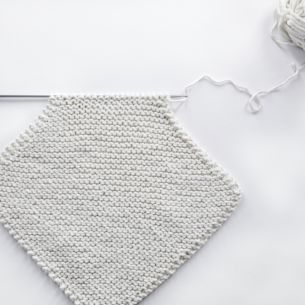 pic of a corner-to-corner dishcloth half knitted, on a knitting needle