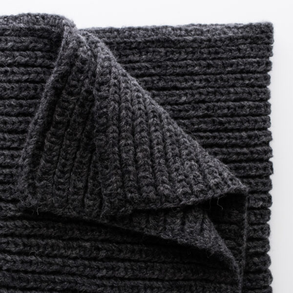 Folded Misty Dewdrop Blanket in bulky black yarn, showcasing the thick fisherman rib stitch pattern and clean edging.