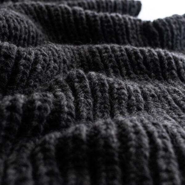 Close-up of the Misty Dewdrop Blanket in black bulky yarn, showing the ribbed texture and soft drape of the fisherman’s rib stitch.