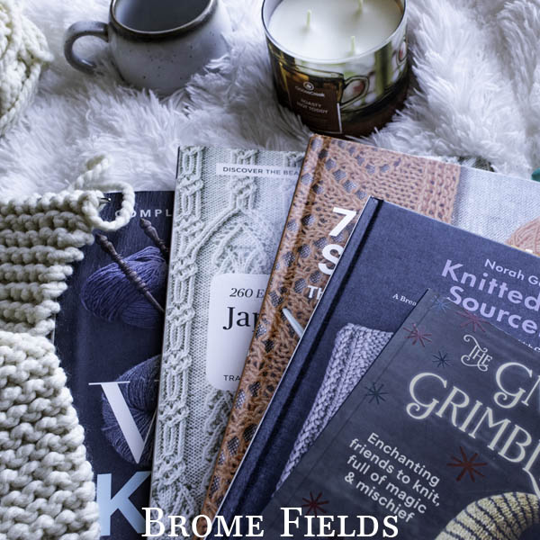 a cozy scene of my 4 favorite knitting books on a faux fur rug with a knitting project, candle and mug.