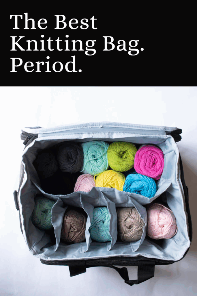 Overhead view of an open gray knitting organizer filled with colorful yarn skeins neatly arranged in compartments. Knitting needles, scissors, and extra yarn lie beside it on a white background.