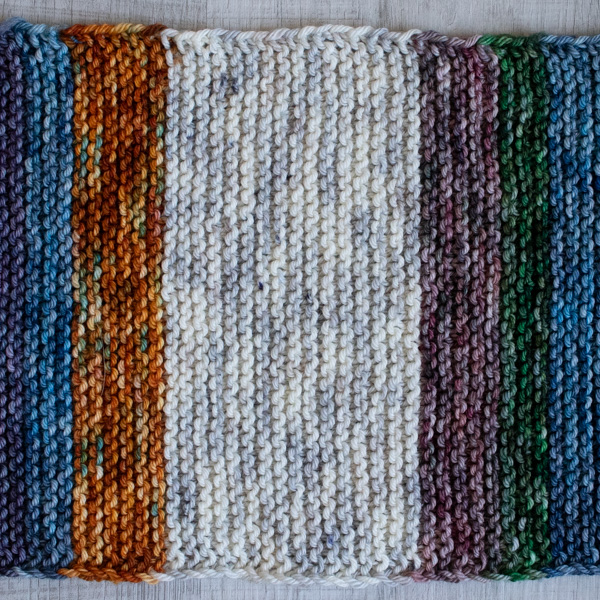 Close-up photo of a worsted yarn swatch in the garter stitch pattern. The front featuring clean color switching. The yarn is soft colorful, showing clear stitch definition and beautiful squishy texture.