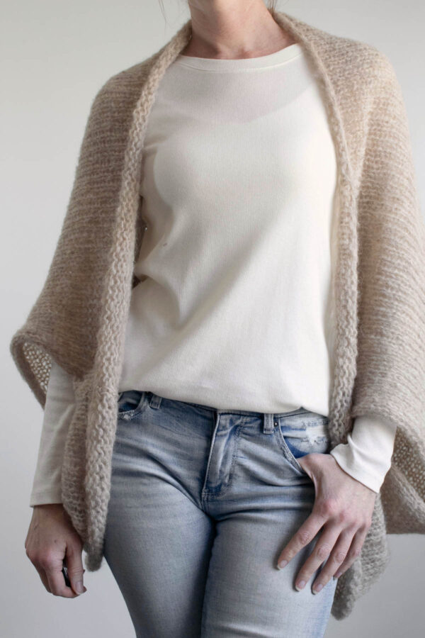 Woman wearing a lightweight summer knit shrug over a cream tee and jeans