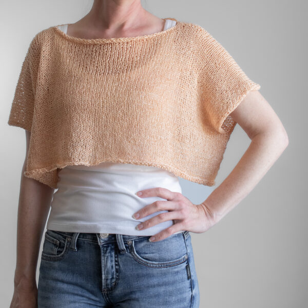 a woman wearing a peach linen knit tee from the front, back, and sides. The boxy cropped top has short sleeves and a wide neckline.