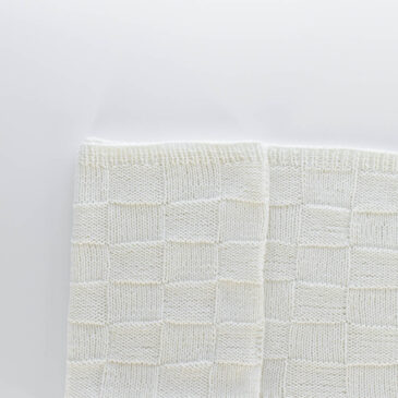 Cottage Lattice Quilted Checkerboard Blanket Pattern Handknit seamless quilt checkerboard knit blanket laying on a white background