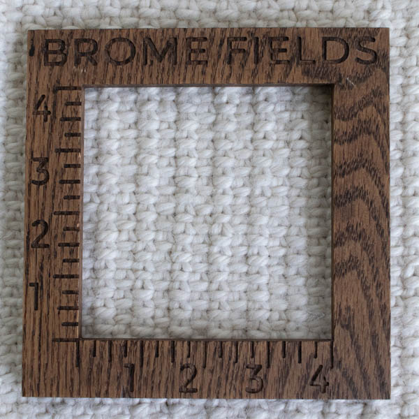 Close-up detail of a linen stitch tote bag, measured with a wooden 4-inch gauge ruler engraved with “Brome Fields.”