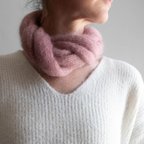 Simple, one skein soft pink lightweight knit scarf worn by a model
