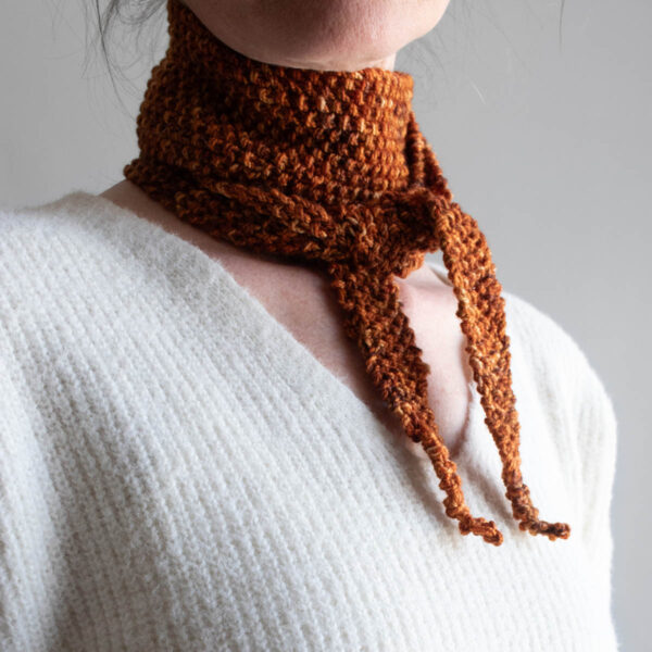 Rust and gold seed stitch skinny scarf worn as a neck kerchief