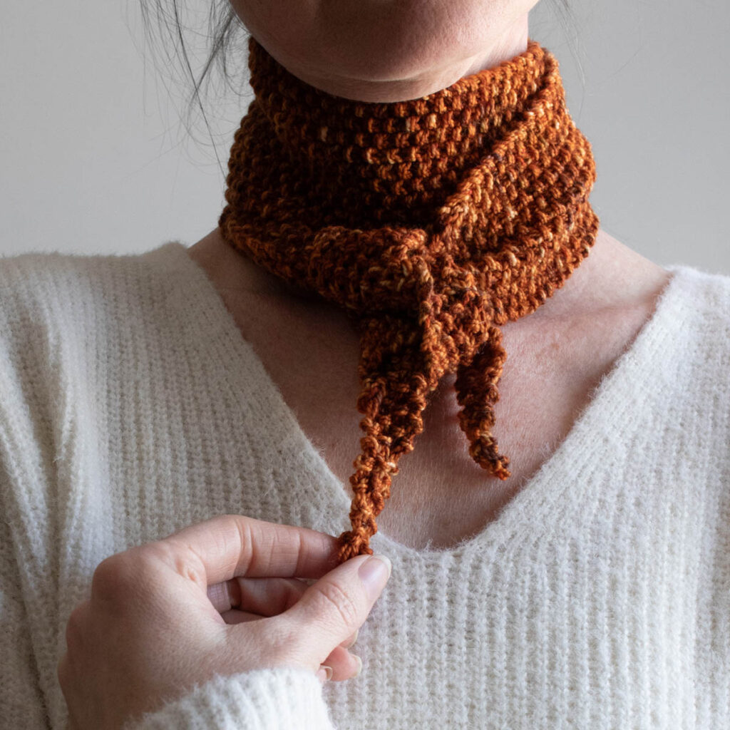 Woman adjusting the knot on her seed stitch skinny scarf
